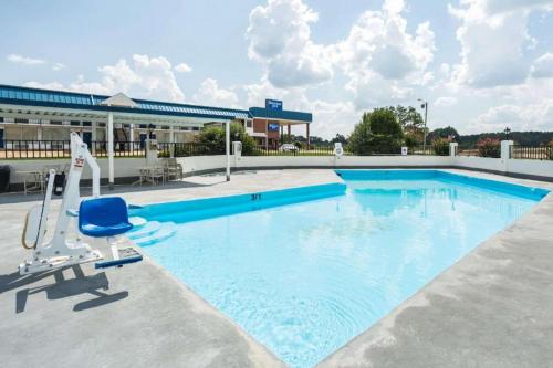 a large swimming pool with a chair and a building at Rodeway Inn in Sardis