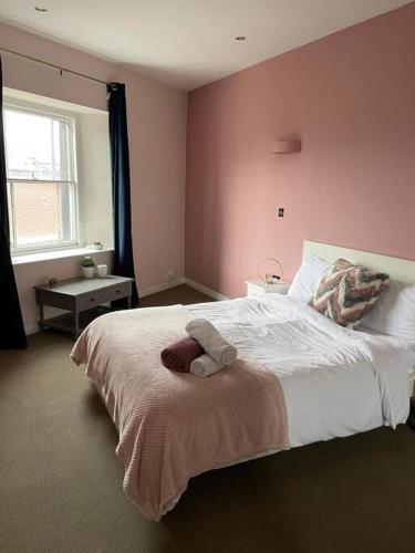 a bedroom with a large bed with pink walls at The Cherry Blossom in Bristol