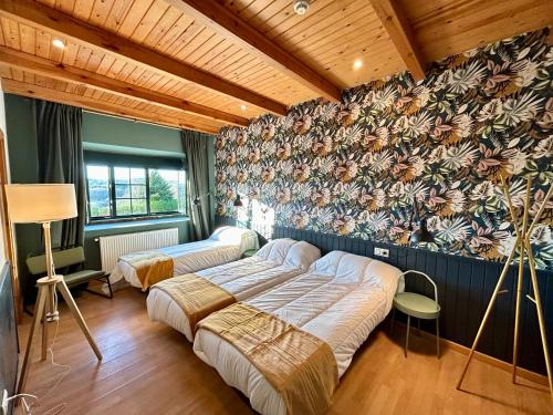 two beds in a bedroom with a floral wall at Casa Bolboreta in Palas de Rei