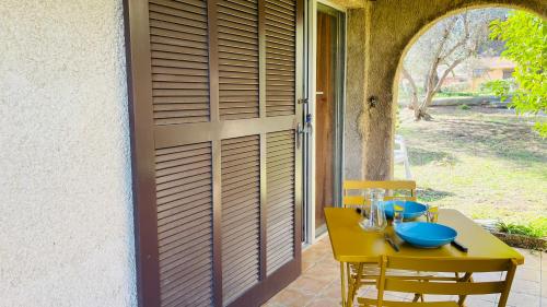 une table et des chaises jaunes sur une terrasse avec une porte dans l'établissement Studio Cocody 6 LUMIO, à Lumio