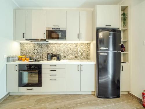 una cucina con mobili bianchi e un frigorifero in acciaio inossidabile di Soma Lux Apartment! a Città di Corfù