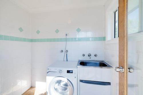 a laundry room with a washing machine and a sink at Spacious House with Pool - 5 min walk to Lake in Wyong