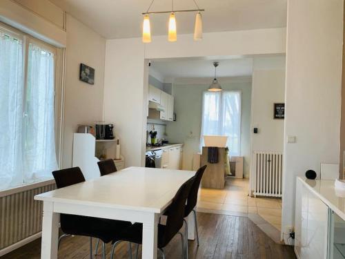 une cuisine et une salle à manger avec une table et des chaises blanches dans l'établissement La maison de Charlotte, à Vierzon