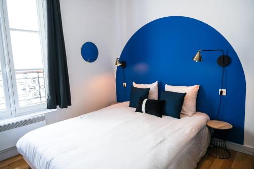 a bed with a blue headboard in a room at La Cour Des Senteurs / F2 Château de Versailles in Versailles
