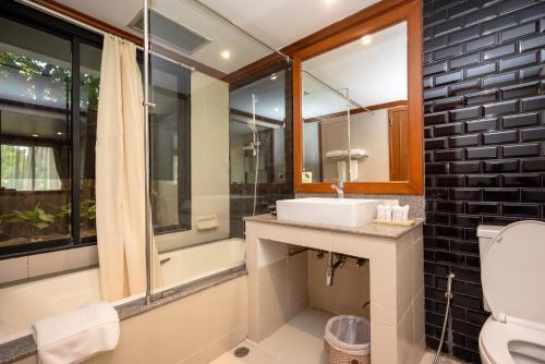 a bathroom with a sink and a tub and a toilet at Comsaed River Kwai Resort in Kanchanaburi