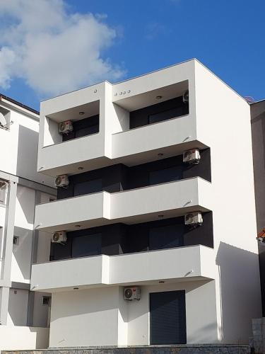 un edificio blanco con balcones en un lateral en Top Apartments, en Dobra Voda