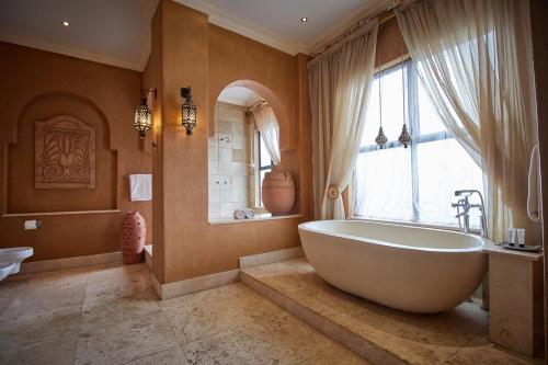 a bathroom with a large tub and a window at Royal Elephant Hotel & Conference Centre in Centurion