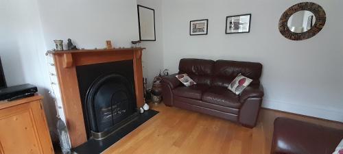 a living room with a leather couch and a fireplace at Peaceful Family Retreat Near Gloucester Road in Bristol
