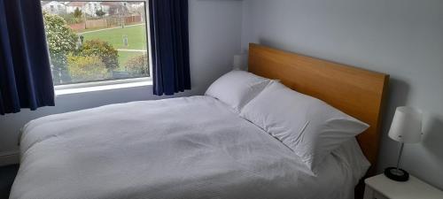 a white bed with a wooden headboard and a window at Peaceful Family Retreat Near Gloucester Road in Bristol