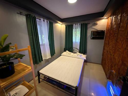 a small room with a bed with green curtains at Amakan Beachfront Private House Bataan in Bagac