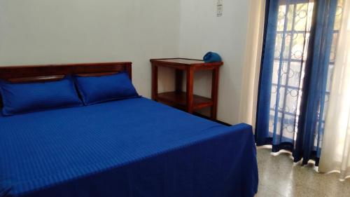 a bedroom with a blue bed with a table and windows at Aquila By Bolgoda Holiday Resort in Moratuwa