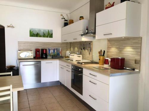 une cuisine avec des armoires blanches et des appareils électroménagers blancs dans l'établissement Appartement moderne à Antibes avec jardin et terrasse, à Antibes
