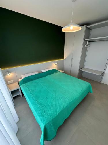 a green bed in a room with a green wall at Woody Green Charming Apartments - Agenzia Cocal in Caorle