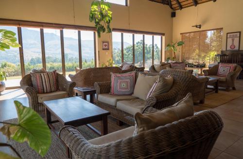 a living room with couches and tables and windows at Silver Hill Lodge in Kamberg Valley