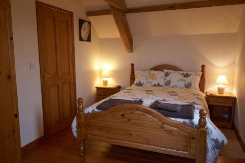 a bedroom with a wooden bed with two lamps on tables at Cnwc Y Boidy Llangrannog in Llangranog