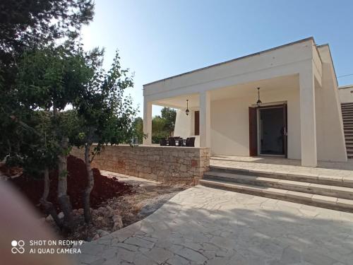 a white building with a brick wall and a door at VILLA IL PIGNO ZONA MALDIVE DEL SALENTO in Marina di Pescoluse