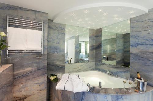 a bathroom with a tub and a large mirror at Sauerland Stern Hotel in Willingen