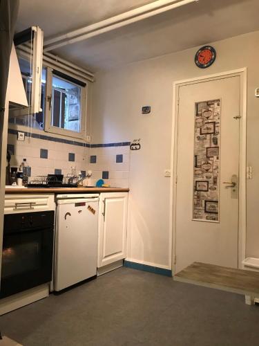 a small kitchen with white appliances and a door at Chez Bibi in Neuilly-sur-Marne