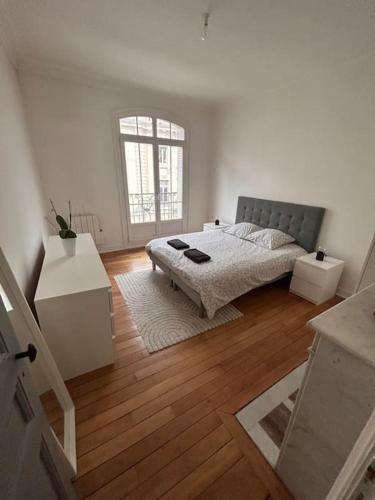 une chambre blanche avec un lit et un parquet dans l'établissement * Le Cathédrale *, à Reims