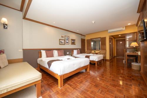 a hotel room with two beds and a table at Comsaed River Kwai Resort in Kanchanaburi
