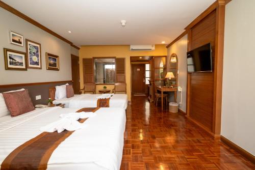 a hotel room with two beds and a television at Comsaed River Kwai Resort in Kanchanaburi