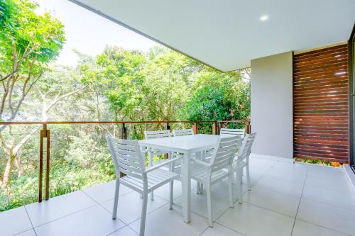 une table et des chaises blanches sur un balcon arboré dans l'établissement The Sanctuary 25, Zimbali Estate, à Ballito
