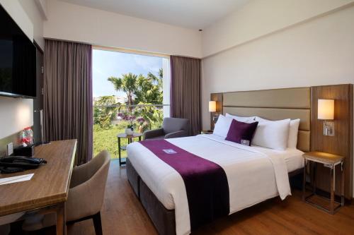 Habitación de hotel con cama grande y escritorio. en Premier Place Surabaya Airport en Sidoarjo