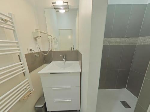 une salle de bain blanche avec un lavabo et une douche dans l'établissement Molière Marseille, à Marseille