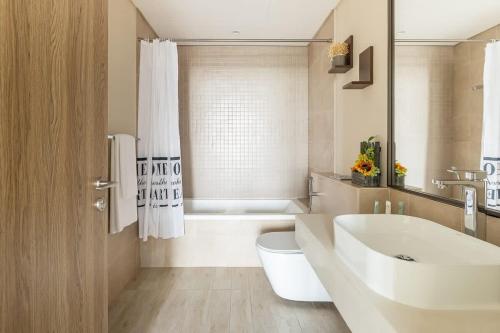 a bathroom with a sink and a toilet and a tub at Frank Porter - 1 Residences West in Dubai