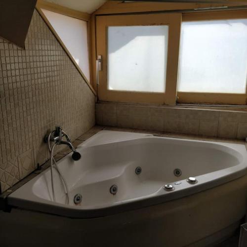 a bath tub in a bathroom with two windows at Νεοκλασική Κατοικία στο Κέντρο in Mytilini