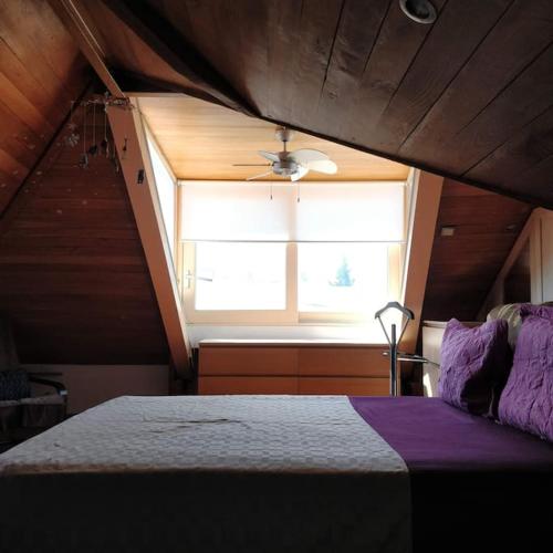 ein Schlafzimmer mit einem Fenster und ein Bett mit lila Bettwäsche in der Unterkunft Νεοκλασική Κατοικία στο Κέντρο in Mytilini