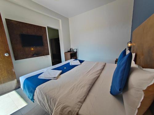 a bedroom with a large bed with blue pillows at Rain Raga Resort in Mahabaleshwar