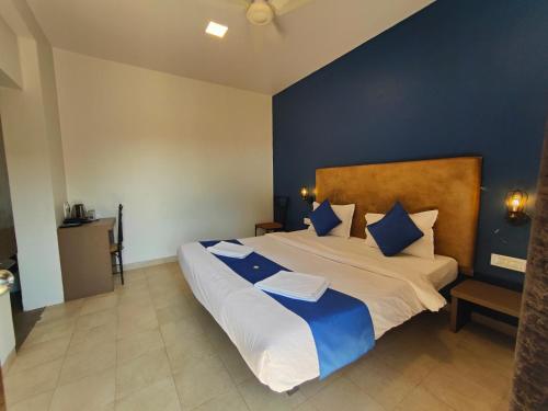 a bedroom with a large bed with blue walls at Rain Raga Resort in Mahabaleshwar