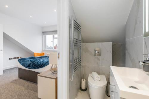 a bathroom with a toilet and a sink and a bed at Luxurious 2 BR - Apartment - Sleeps 6 in London