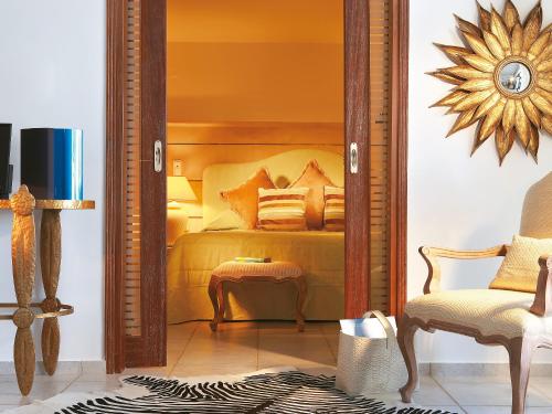 a bedroom with a bed and a chair and a mirror at Grecotel Creta Palace in Rethymno Town