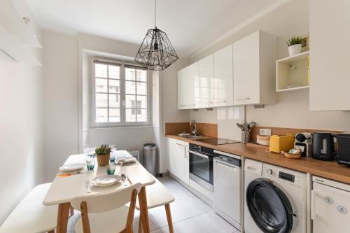 une cuisine avec des armoires blanches et une table et des chaises dans l'établissement Chez Léon - Appt à 500m des plages, à Saint-Malo