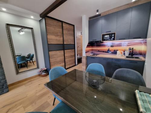 a kitchen with a glass table and blue chairs at Alpha lux C520 - Aparthotel Vucko - Privatni apartman in Jahorina