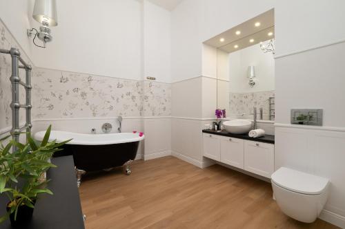 a bathroom with two sinks and a tub and a toilet at Sage Green Apartment Piotrkowska in Łódź by Renters in Łódź