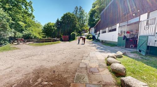 a couple of people walking down a dirt road next to a barn at Reiterpension Marlie in Scharbeutz