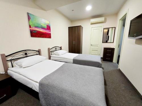a hotel room with two beds and a flat screen tv at Wellotel Chornomorsk in Chornomorsk