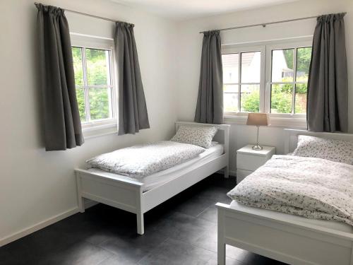 a bedroom with two beds and two windows at Ferienwohnung auf einem Reiterhof in Scharbeutz