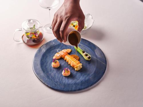 a person pouring sauce on a plate of food at Relais Bernard Loiseau in Saulieu