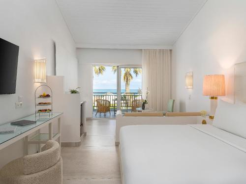 a hotel room with a bed and a view of the ocean at Grecotel Creta Palace in Rethymno Town