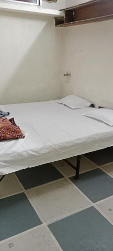 uma cama num quarto com lençóis brancos e almofadas em Shree Shivaya Guest House em Ujaim