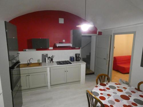 - une cuisine avec un mur rouge et une table dans une chambre dans l'établissement Maison de village, à Baix