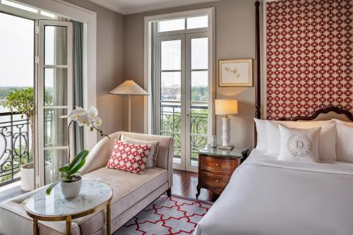 a bedroom with a bed and a couch and windows at Mia Saigon – Luxury Boutique Hotel in Ho Chi Minh City