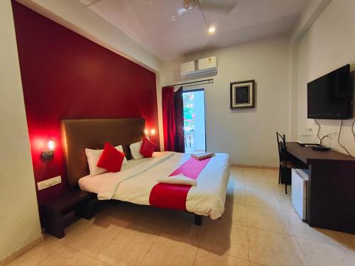 a bedroom with a bed with red walls and a desk at Rain Raga Resort in Mahabaleshwar