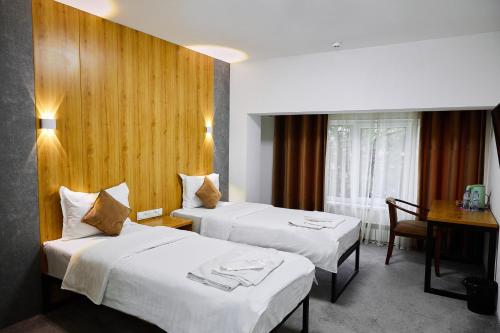 Cette chambre comprend 2 lits et une table. dans l'établissement Art Plaza Hotel, à Tachkent