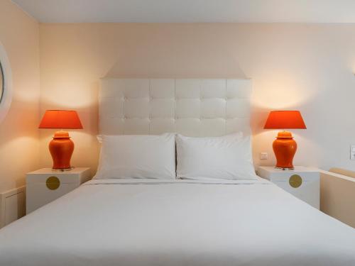 a bedroom with a large white bed with two lamps at Grecotel Creta Palace in Rethymno Town