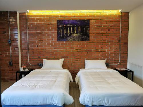 two beds in a room with a brick wall at BETONG HELLO GUESTHOUSE in Betong